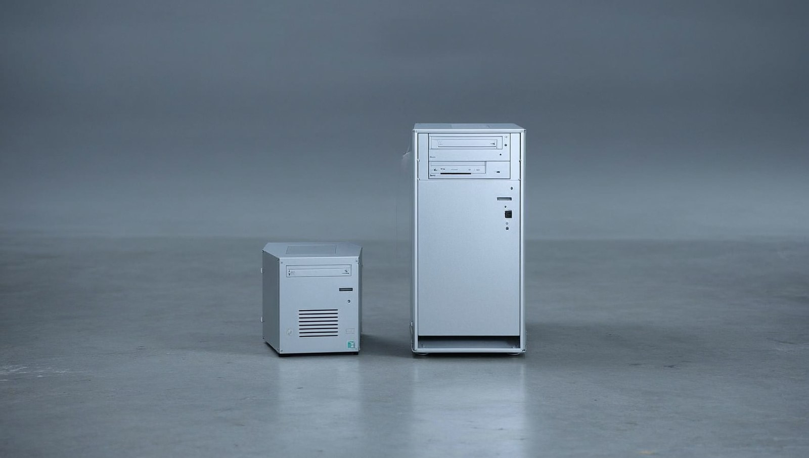 Two aluminium desktop computers of different sizes side by side on a workbench with steel calipers.